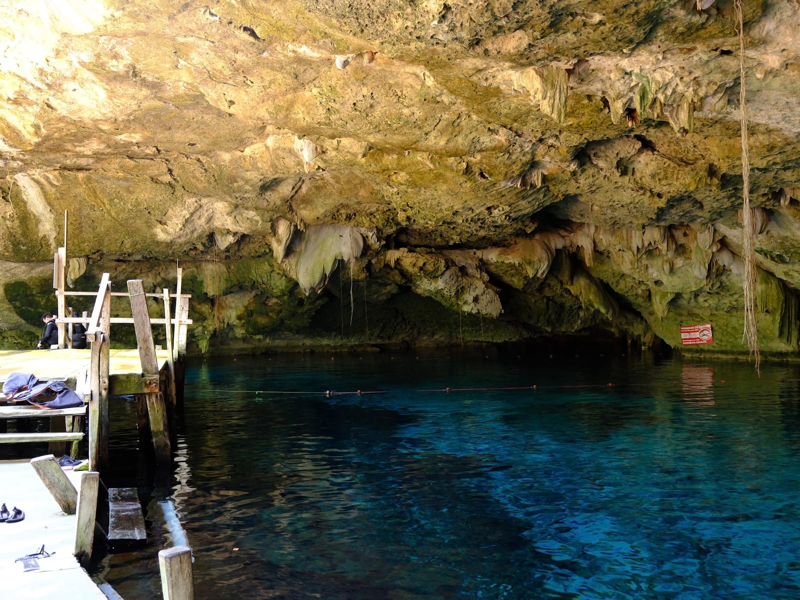 Wooden platform and clear water beneath the stalactites of Cenote Dos Ojos