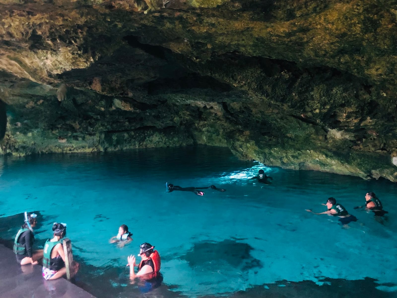 Snorkelers in life jackets in the turquoise water of Cenote Dos Ojos