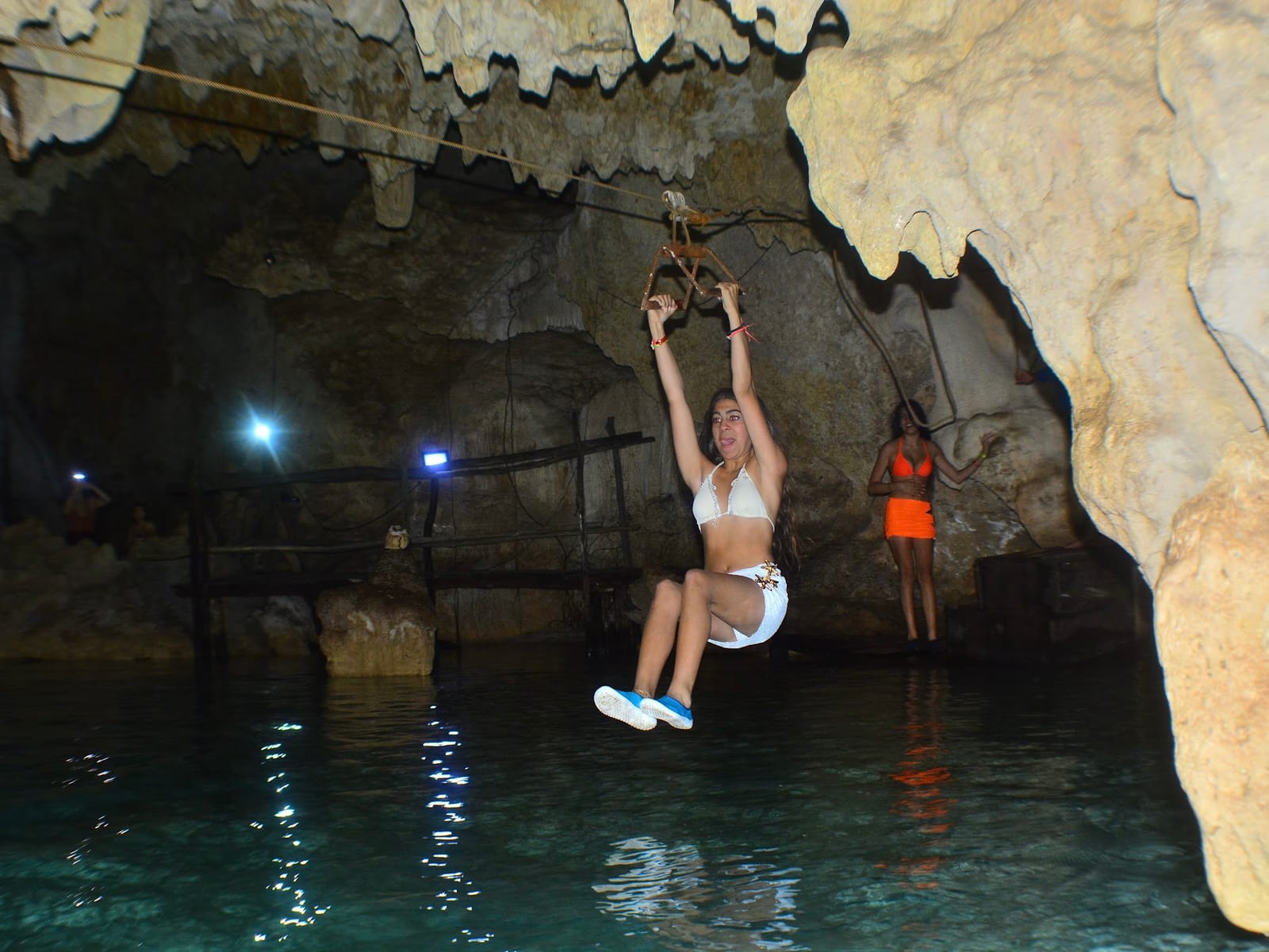 Zipline over turquoise water inside the Cenote Alux cavern