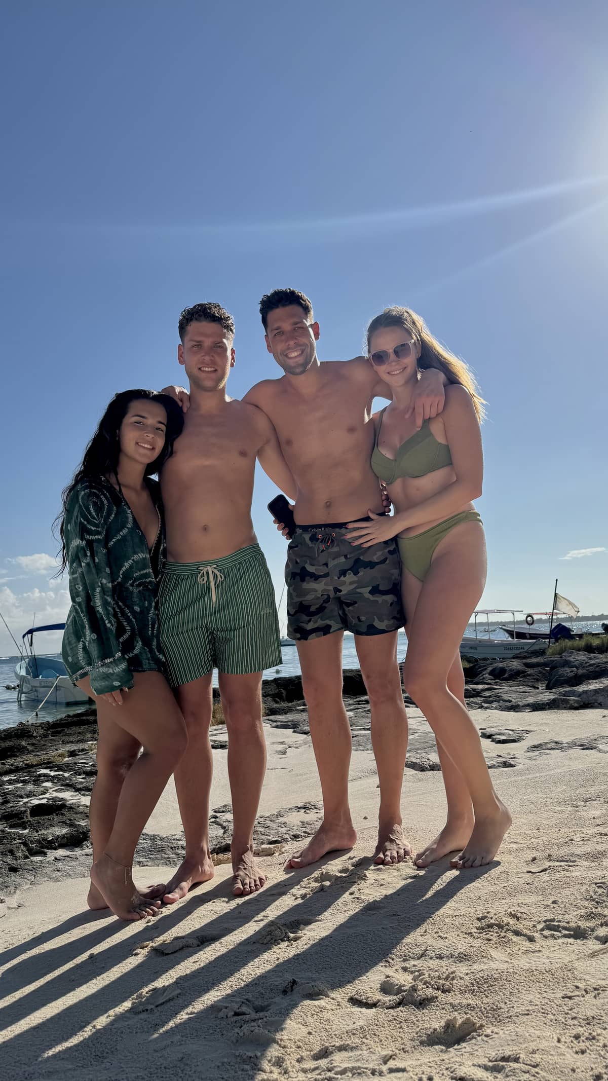 Four happy guests posing on white sand at Akumal Bay after an Akbay Tours experience
