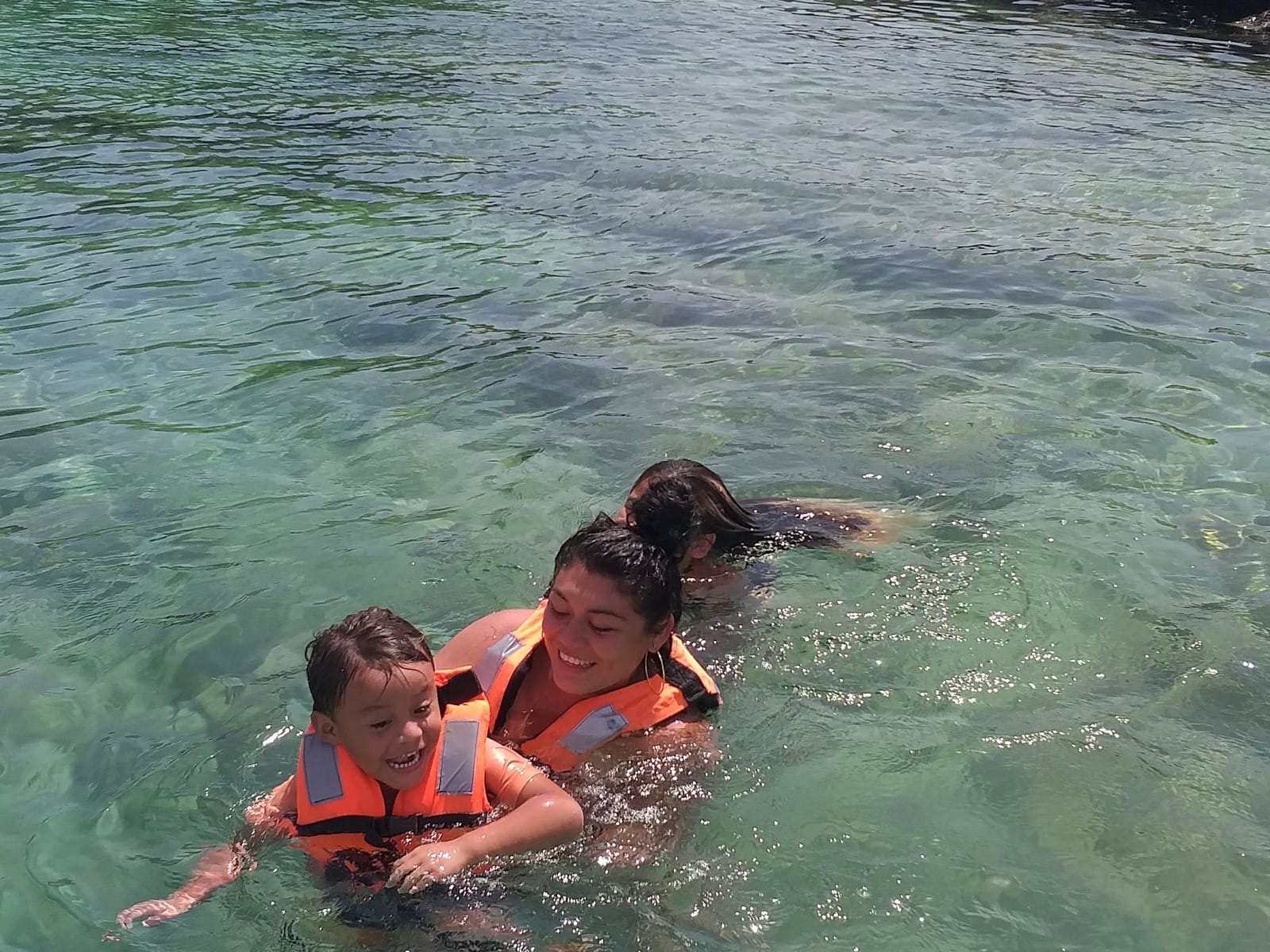 Mum and son in life jackets smiling in the clear lagoon water