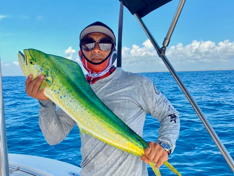 Crew member holding a freshly caught mahi-mahi on board