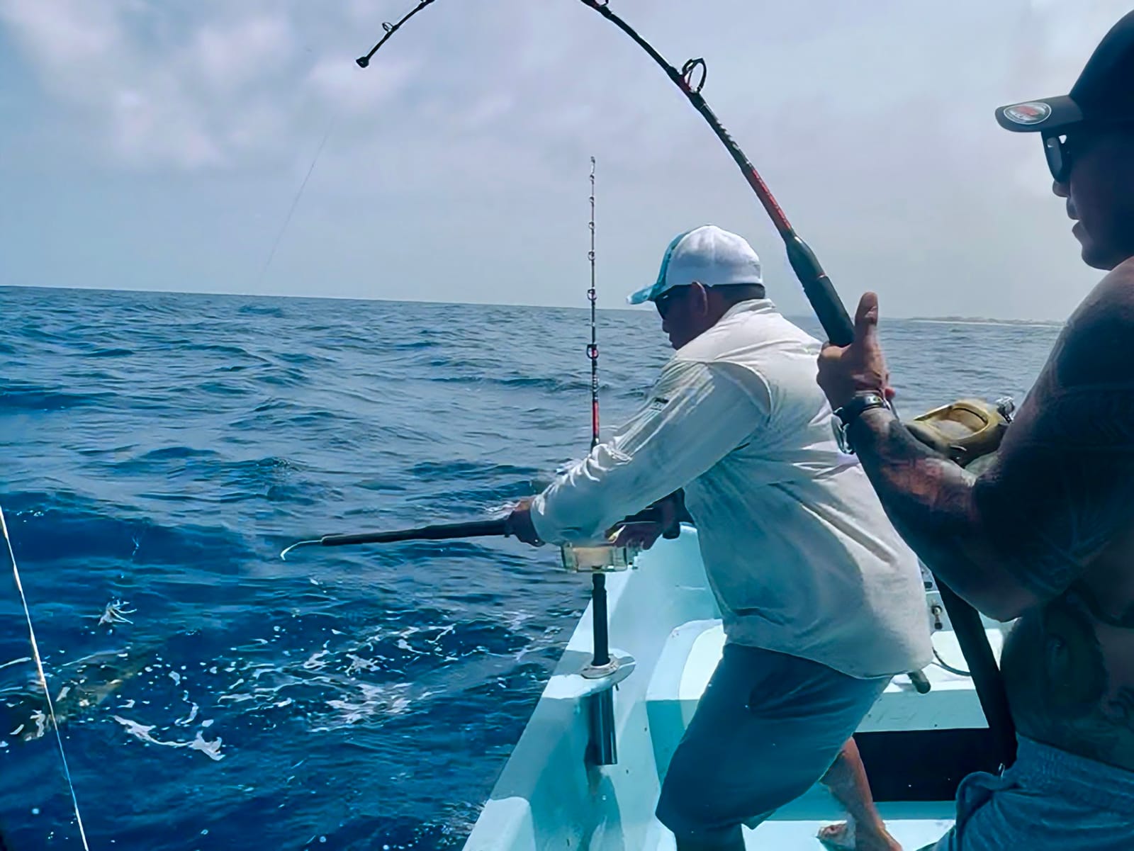 Trolling: a rod bends under a bite while the mate brings the fish alongside the boat