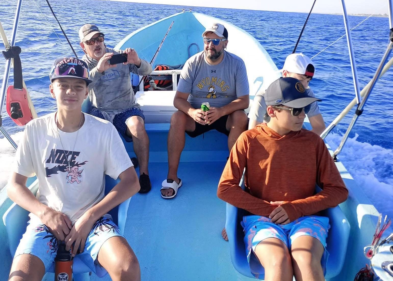 Family with teenagers seated on the fishing boat out at sea