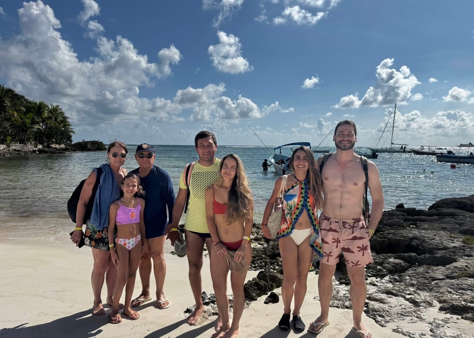 Group of guests on the beach with the boats behind