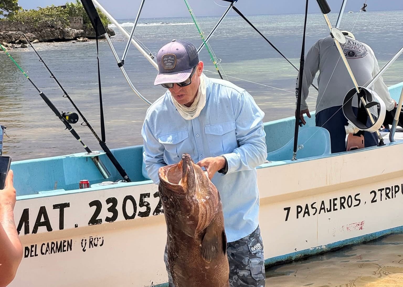Guest holding a grouper next to the boat at the shore