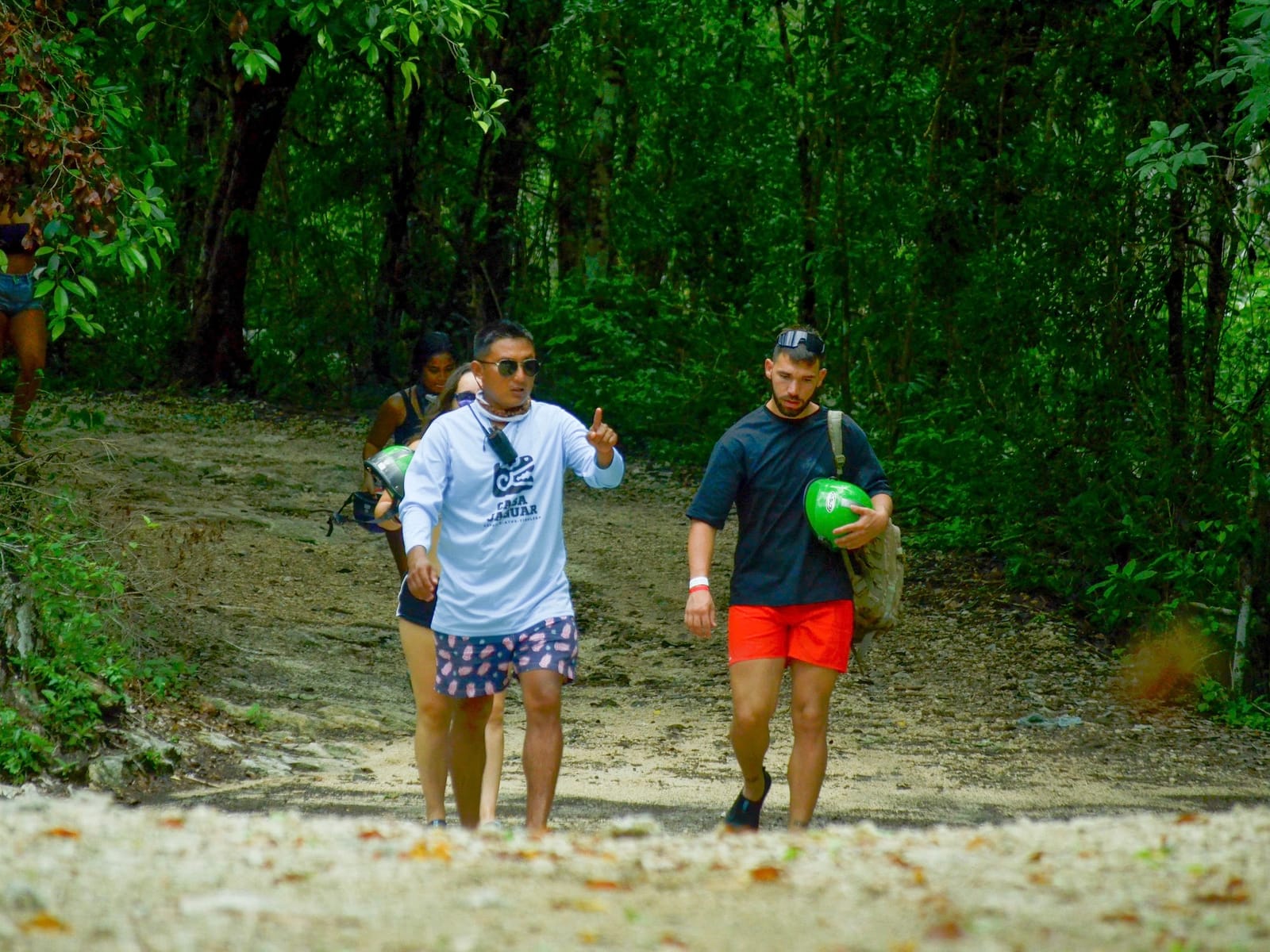 Jungle guide points the way for guests carrying their helmets