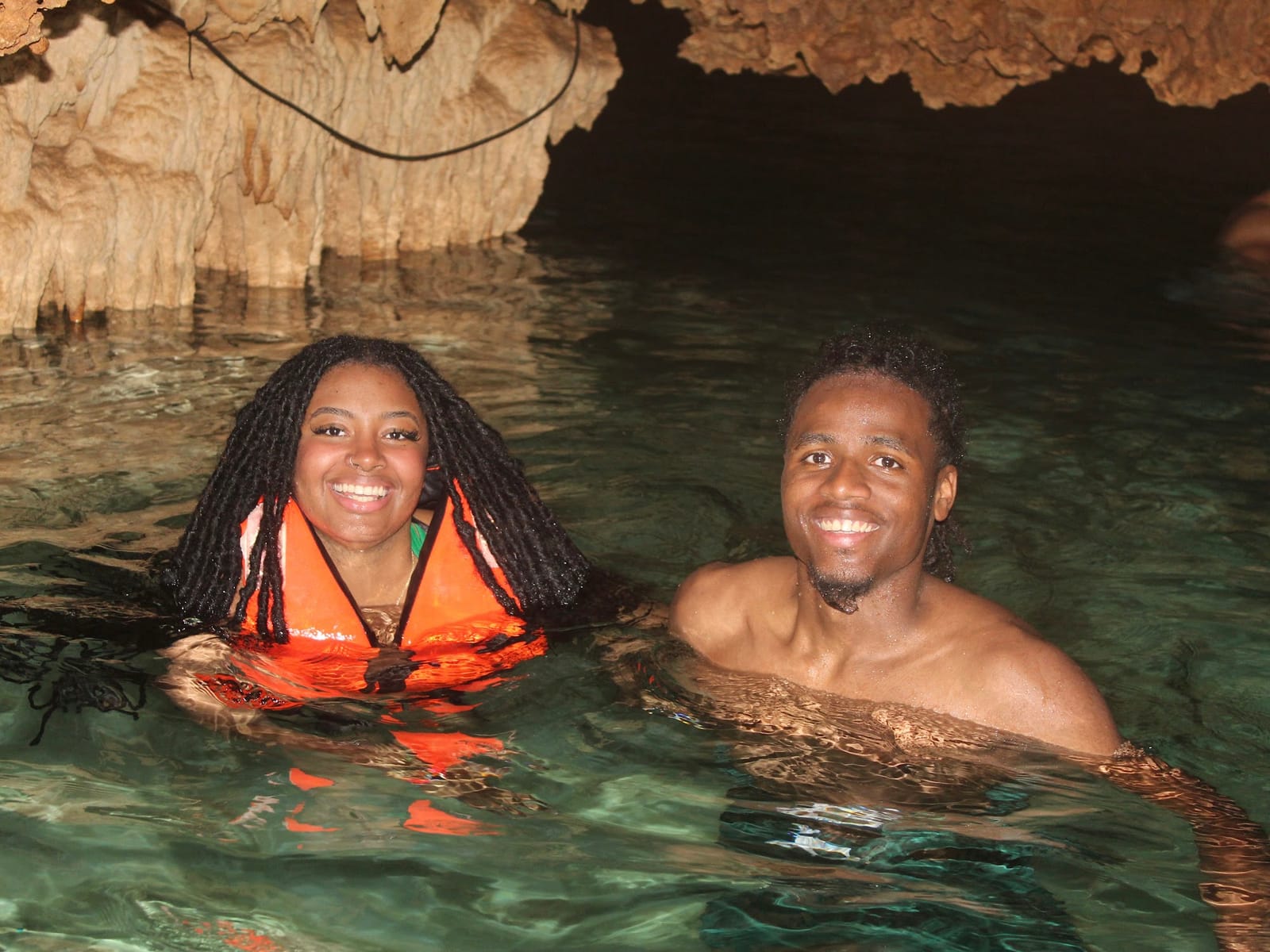 Smiling couple in the clear water of Cenote Alux