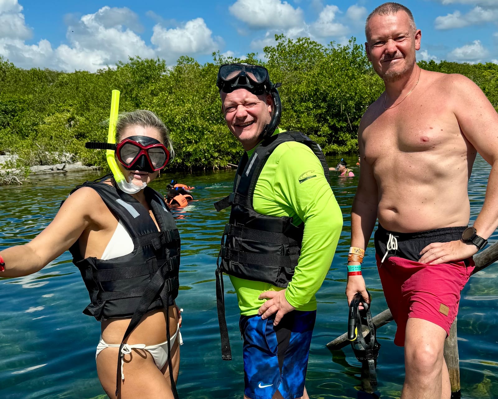 Three guests with snorkel gear in the clear water of Yal-Kú Lagoon, mangroves behind